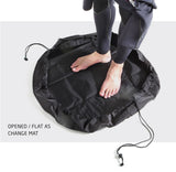 person in wetsuit standing on changed mat with a drawstring