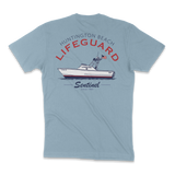 A light blue short-sleeve t-shirt shown from the back, featuring a graphic print of a 'Huntington Beach Lifeguard' boat on the back with red and black lettering.