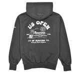 Back view of a charcoal heavyweight hooded sweatshirt featuring a large white US Open of Surfing graphic with a surfboard, ocean waves, sun illustration, and Huntington Beach Pier artwork. The pullover hoodie has a vintage-washed finish, ribbed cuffs and waistband, and is displayed on a clean white background.