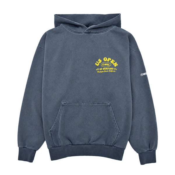 front view of a indigo blue heavyweight hooded sweatshirt featuring on chest a yellow US Open of Surfing graphic with a surfboard, ocean waves, sun illustration, and Huntington Beach Pier artwork in yellow. The pullover hoodie has a vintage-washed finish, ribbed cuffs and waistband, and is displayed on a clean white background.
