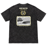 back of a washed black t-shirt with image of a wave with HB peir in background