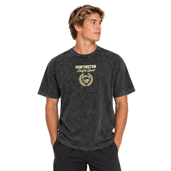 front of person wearing washed black t-shirt with small logo with text. Huntington Surf & Sport, El Niño 2026
