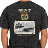 back of person wearing a washed black t-shirt with image of a wave with HB peir in background