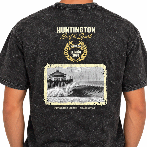 back of person wearing a washed black t-shirt with image of a wave with HB peir in background