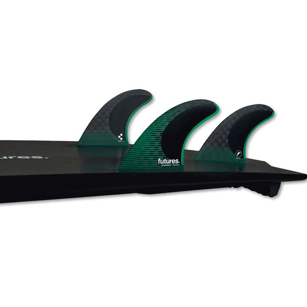 tail of black surfboard with 3 green fins
