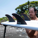 jordy smith holding surfboard with 3 surf fins attached