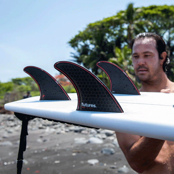 jordy smith holding surfboard with 3 surf fins attached