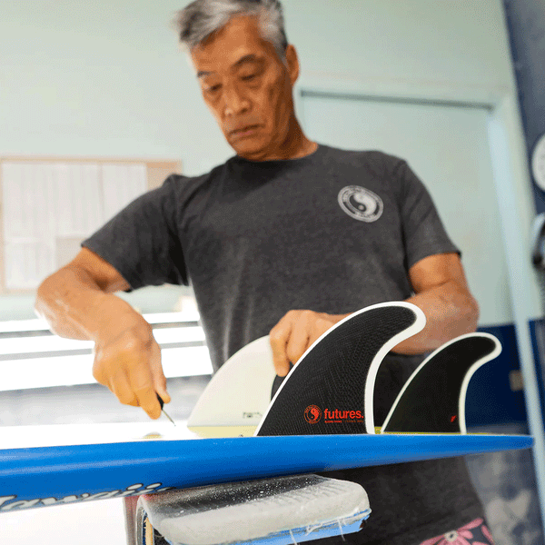 glen pang installing surf fins on a surfboard