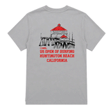 Back view of a light gray US Open of Surfing t-shirt laid flat. The back graphic features an illustration of the Huntington Beach Pier with bright red rooftops above bold red text reading "US Open of Surfing Huntington Beach California." The shirt is made from medium-weight cotton and showcases a clean surf-inspired design celebrating Huntington Beach's iconic surf culture.