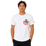 Front-facing studio product photo of a male model wearing a white US Open of Surfing t-shirt against a clean white background. The shirt features a small left-chest graphic of the Huntington Beach Pier with red rooftops and black linework above red text reading “US Open of Surfing Huntington Beach California.” The model stands facing forward with hands in pockets, showcasing the shirt’s relaxed fit and surf-inspired design.