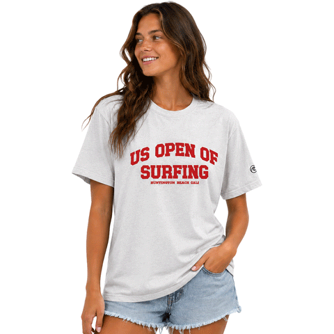 Woman wearing a light gray WSL US Open of Surfing boyfriend-fit T-shirt with red graphic on a white background.
