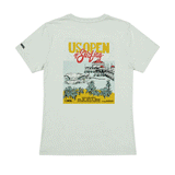Women's light seafoam T-shirt shown from the back with a colorful 2026 US Open of Surfing Huntington Beach graphic featuring the pier, ocean waves, and palm trees.