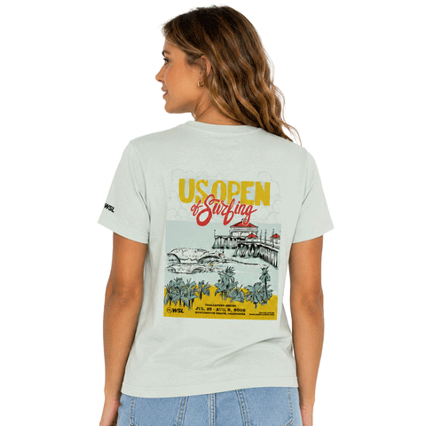 Women's light seafoam T-shirt shown from the back with a colorful 2026 US Open of Surfing Huntington Beach graphic featuring the pier, ocean waves, and palm trees.