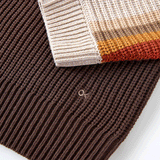 close up of small logo on knit sweater with stripes that are different shades of brown