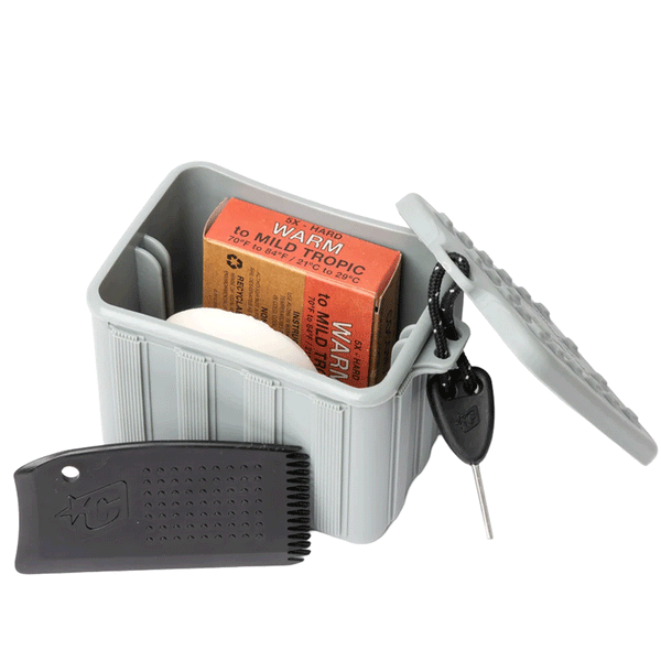 grey tub with lid off and 2 bars of wax in tub and wax comb and surf fin key on white background